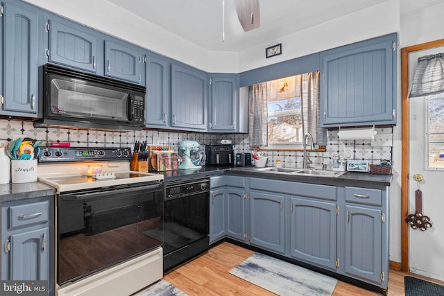 kitchen featuring blue cabinets, sink, backsplash, black appliances, and light wood-type flooring