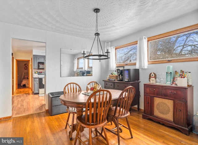 dining space featuring light hardwood / wood-style floors, a chandelier, and a textured ceiling