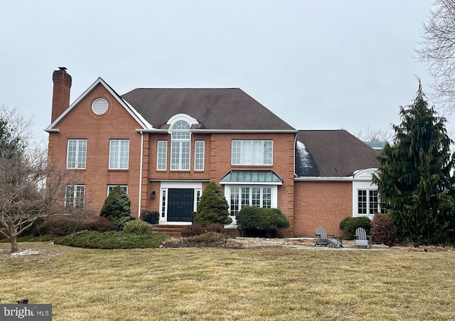 view of front of property featuring brick siding, a chimney, and a front lawn