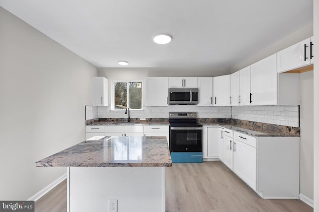 kitchen featuring appliances with stainless steel finishes, stone countertops, tasteful backsplash, white cabinetry, and sink