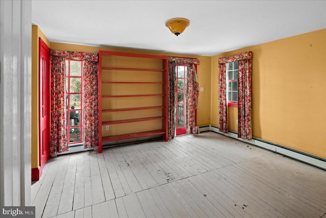 spare room featuring baseboard heating and hardwood / wood-style floors