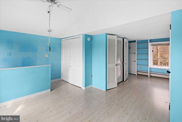 interior space featuring a ceiling fan, wood finished floors, baseboards, a baseboard radiator, and vaulted ceiling