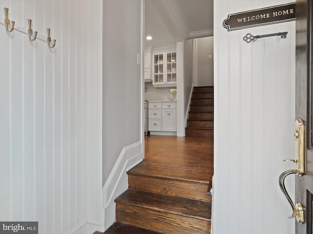 stairway with hardwood / wood-style flooring and ornamental molding