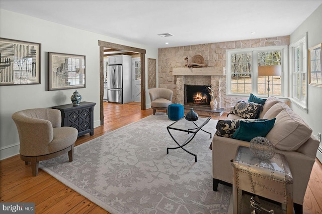 living area featuring a fireplace, wood finished floors, and visible vents