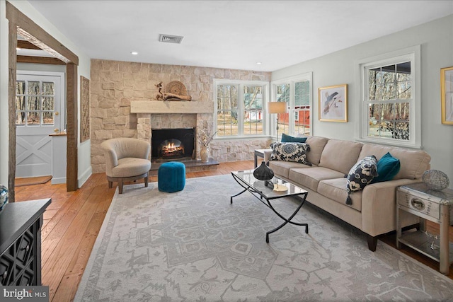 living room featuring light wood-type flooring, a fireplace, and visible vents