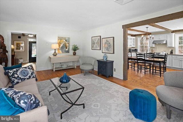 living area with a chandelier, baseboards, and light wood finished floors