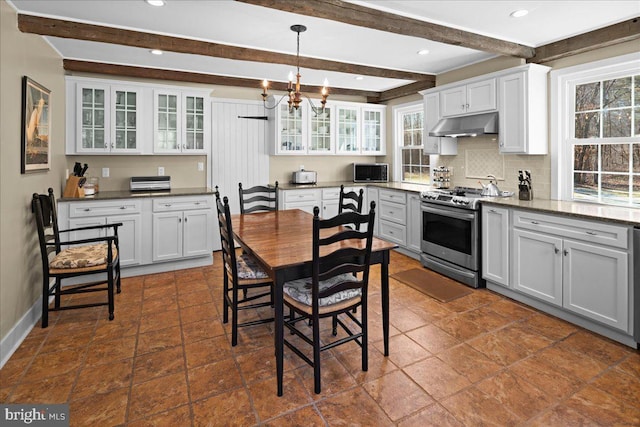 kitchen with under cabinet range hood, stainless steel gas range, glass insert cabinets, and white cabinets