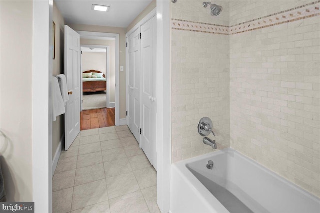 bathroom with a closet, ensuite bathroom, shower / tub combination, baseboards, and tile patterned floors