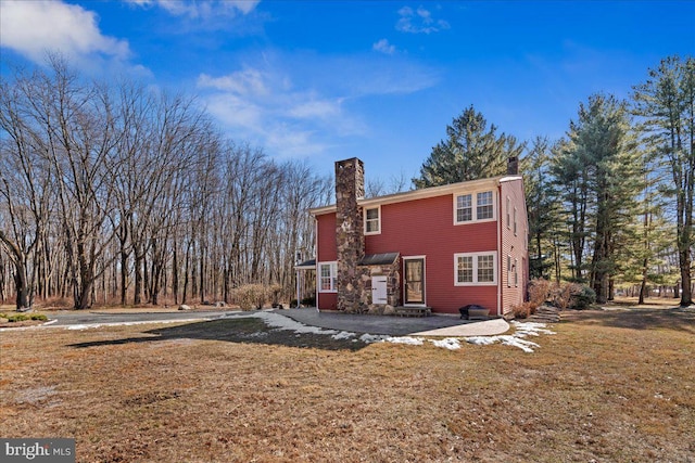 back of house with a lawn and a chimney