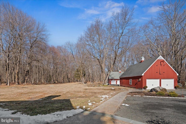 view of yard with a garage, aphalt driveway, and an outdoor structure