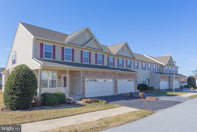 multi unit property with a garage, aphalt driveway, a porch, and roof with shingles