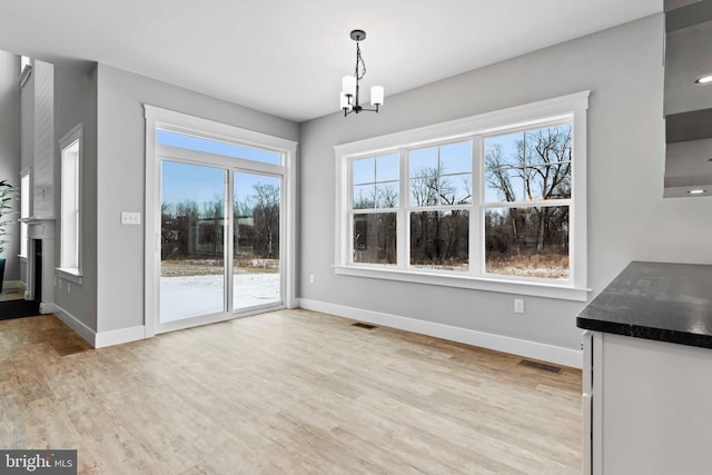 unfurnished dining area featuring an inviting chandelier and light hardwood / wood-style flooring