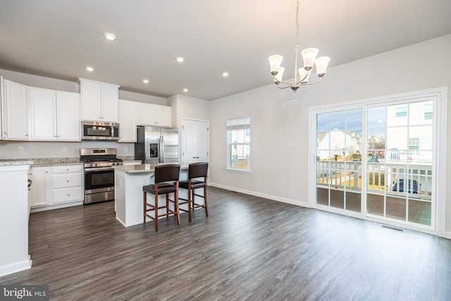 kitchen featuring a breakfast bar, white cabinets, hanging light fixtures, a center island, and stainless steel appliances