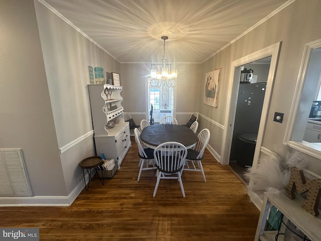 dining space featuring visible vents, baseboards, wood finished floors, an inviting chandelier, and crown molding