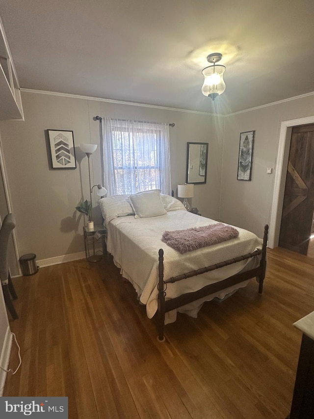 bedroom featuring crown molding, baseboards, and wood finished floors