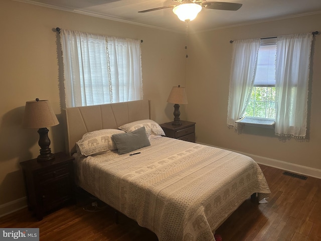 bedroom featuring a ceiling fan, visible vents, baseboards, ornamental molding, and dark wood-style floors