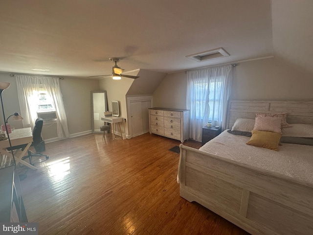 bedroom with ceiling fan, attic access, vaulted ceiling, and wood finished floors