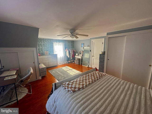 bedroom featuring dark wood-type flooring, ceiling fan, and wallpapered walls