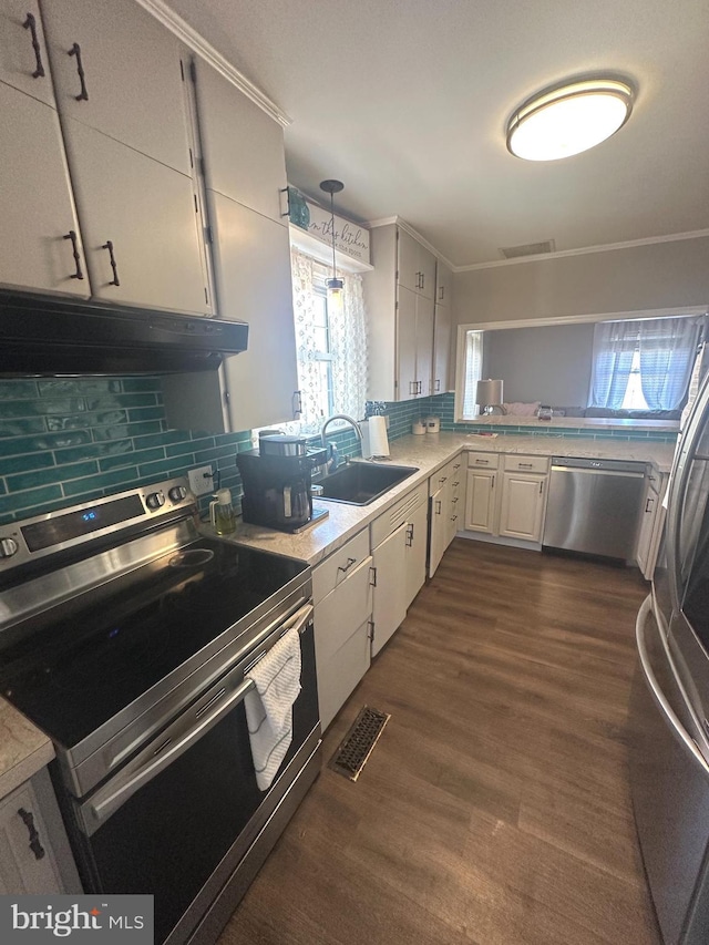 kitchen with under cabinet range hood, stainless steel appliances, a sink, visible vents, and backsplash