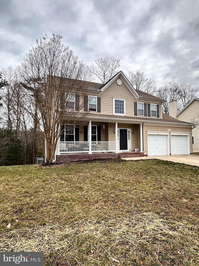 traditional-style home with covered porch, driveway, a front lawn, and a garage