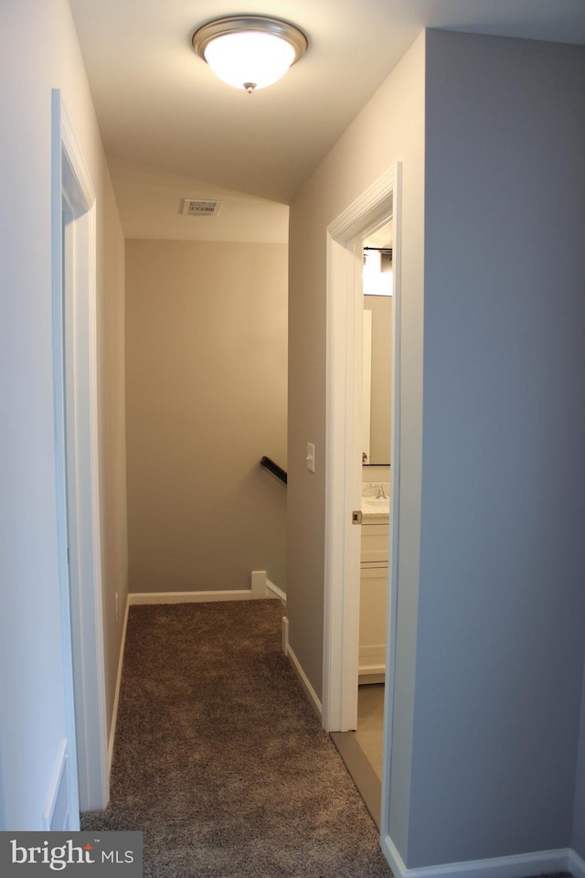 hall featuring sink and dark carpet