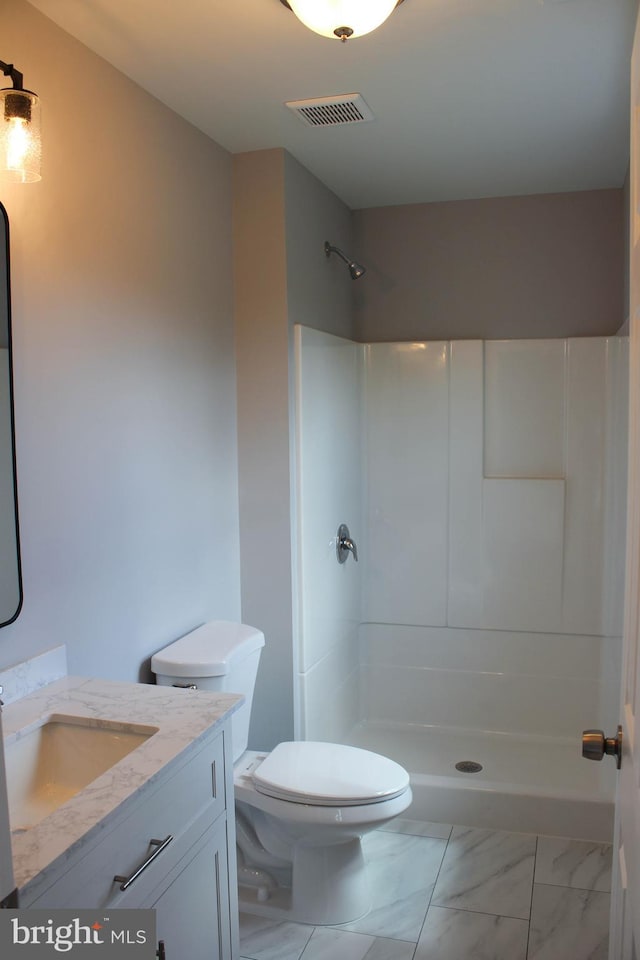 bathroom featuring vanity, walk in shower, and toilet