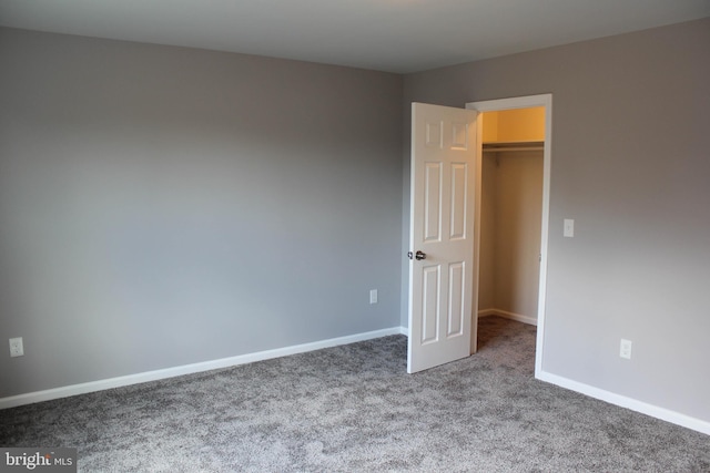 unfurnished bedroom with a walk in closet and carpet