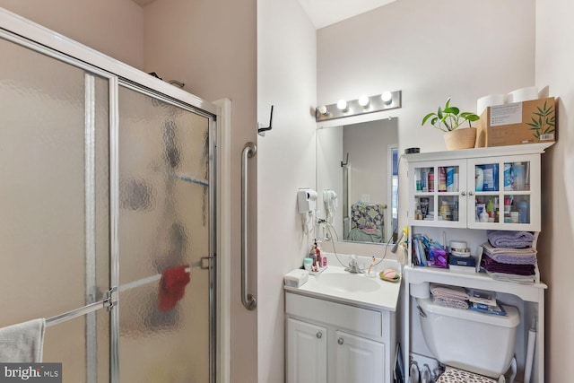 bathroom with vanity, a shower with door, and toilet