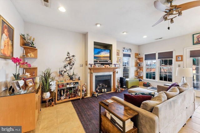 living room with ceiling fan, a fireplace, and light tile patterned floors