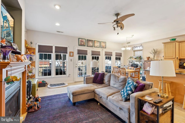 tiled living room featuring ceiling fan with notable chandelier