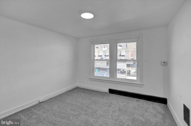 empty room featuring a baseboard radiator and carpet