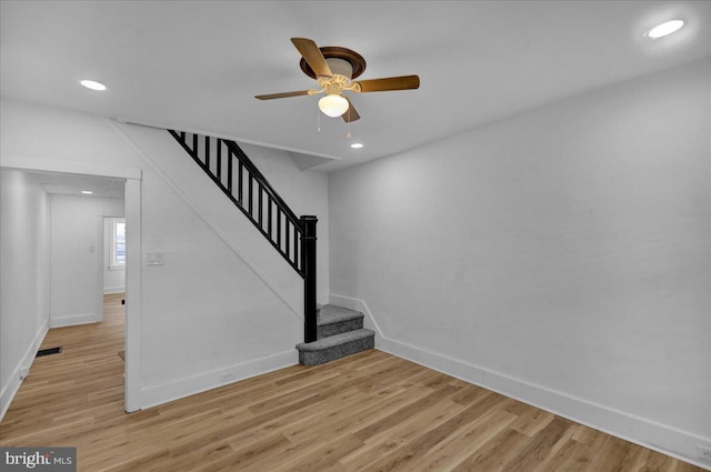 stairs featuring ceiling fan and hardwood / wood-style floors