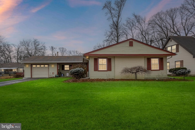 single story home featuring a garage and a yard