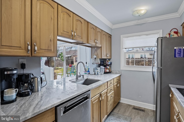 kitchen featuring light stone countertops, crown molding, stainless steel appliances, and a sink