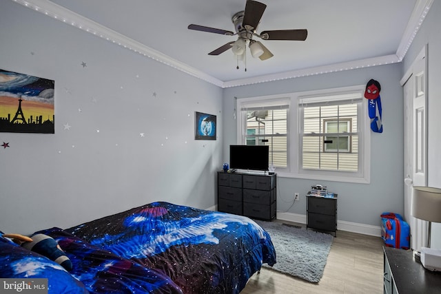 bedroom with baseboards, light wood-type flooring, a ceiling fan, and crown molding