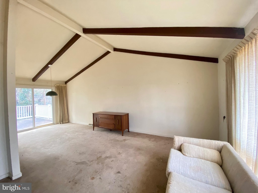 unfurnished living room with vaulted ceiling with beams and carpet flooring