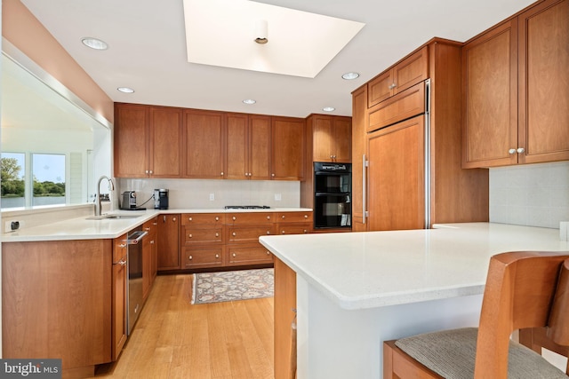 26372 Westerly Rd, Easton, MD 21601 - kitchen with a peninsula, a sink, paneled refrigerator, brown cabinetry, and recessed lighting