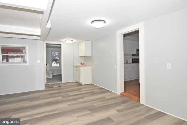 kitchen with white cabinetry, decorative backsplash, and light hardwood / wood-style flooring