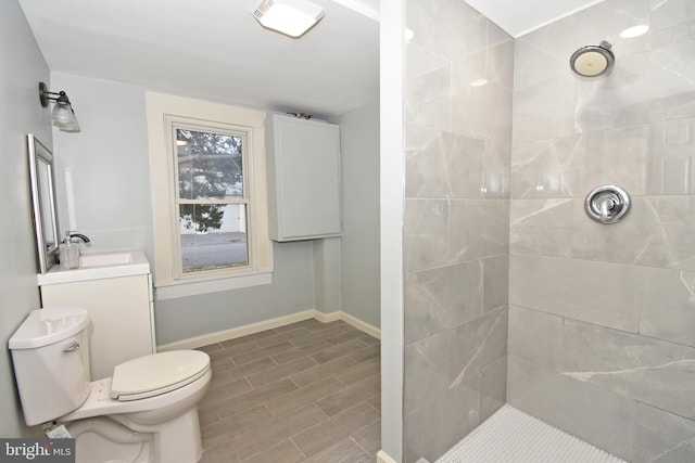 bathroom with a tile shower, vanity, and toilet