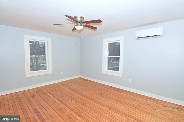 empty room with ceiling fan, an AC wall unit, and light wood-type flooring