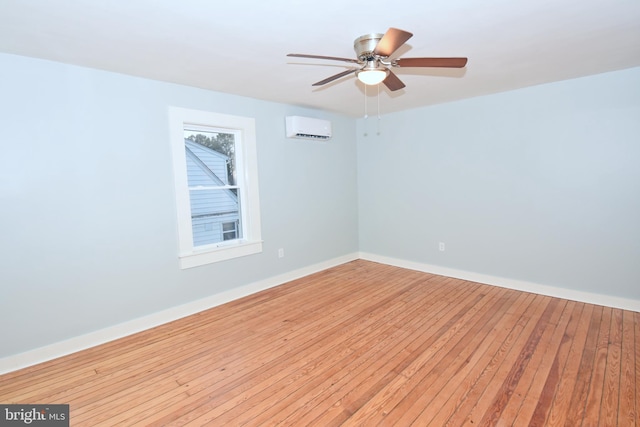 unfurnished room featuring ceiling fan, a wall mounted AC, and light hardwood / wood-style floors