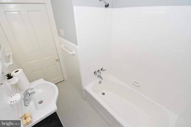 bathroom with tub / shower combination, sink, and tile walls