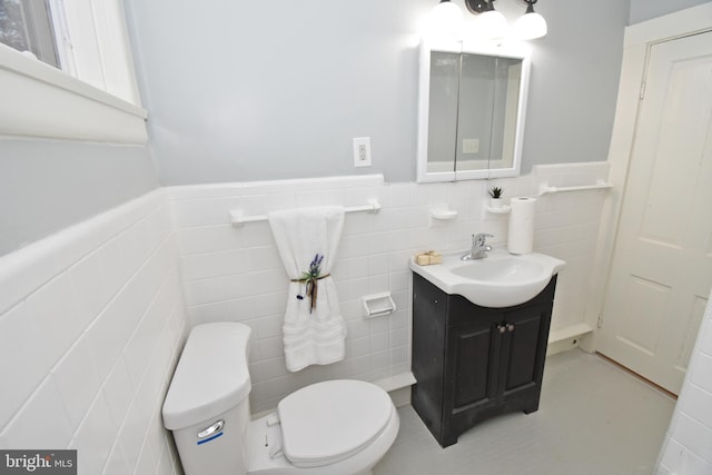 bathroom featuring vanity, tile walls, and toilet