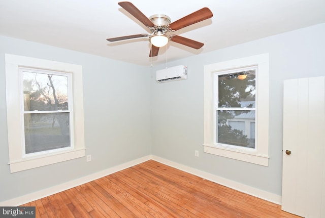 spare room featuring hardwood / wood-style flooring, ceiling fan, and a wall mounted AC