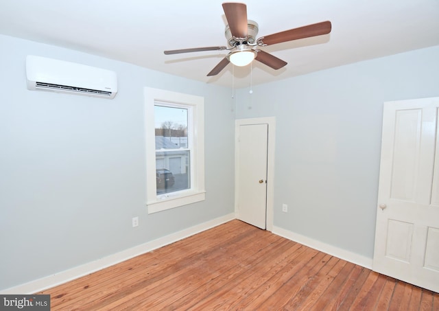 spare room featuring ceiling fan, a wall mounted AC, and light hardwood / wood-style floors