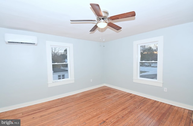 spare room featuring hardwood / wood-style flooring, ceiling fan, and an AC wall unit