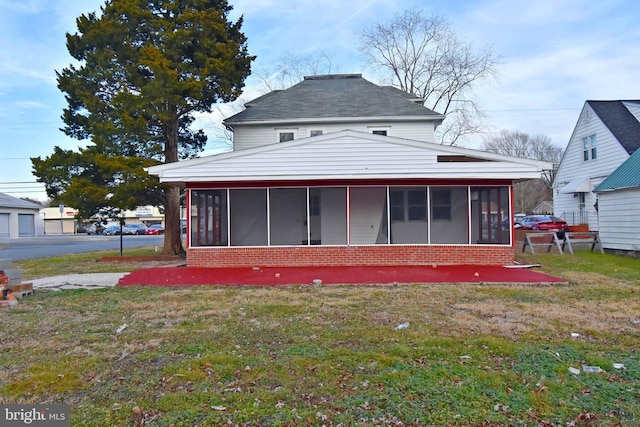 rear view of house with a sunroom and a lawn