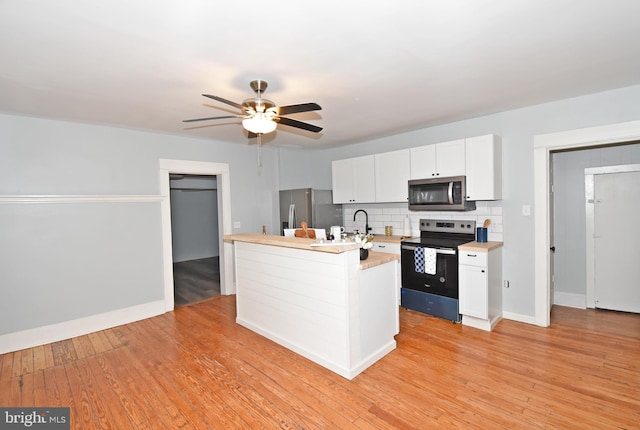 kitchen with stainless steel appliances, a center island with sink, white cabinets, and light hardwood / wood-style floors