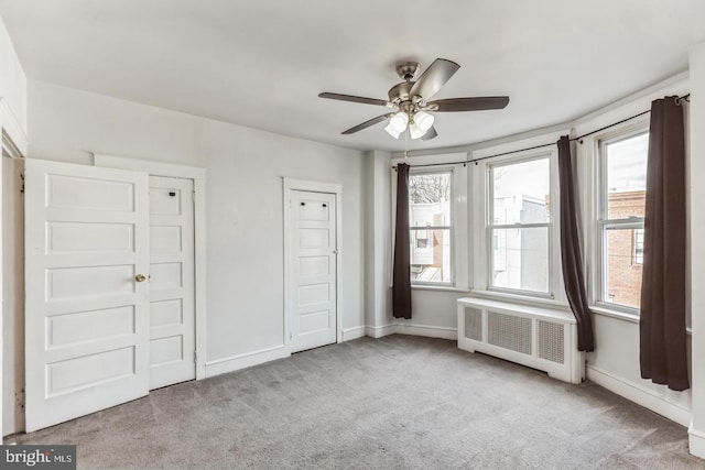 unfurnished bedroom with light carpet, radiator, and ceiling fan