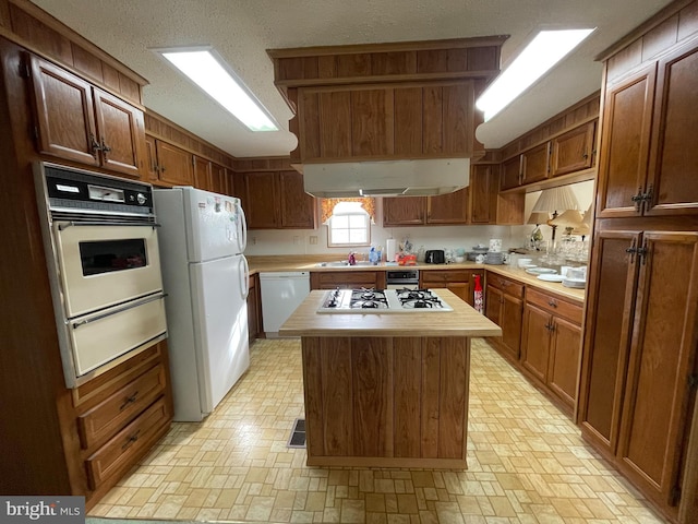 kitchen featuring a kitchen island, white appliances, and a textured ceiling